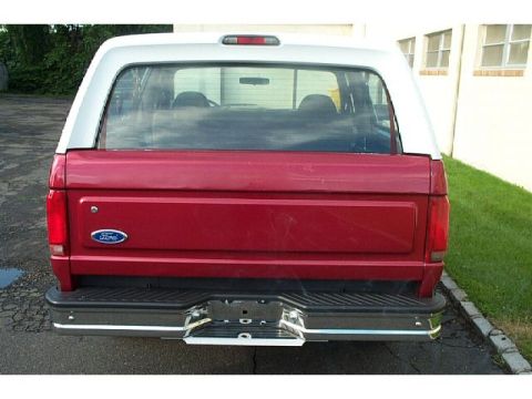 1995 Ford Bronco - Rear view of a red and white Ford Bronco with a chrome bumper and visible Ford emblem.