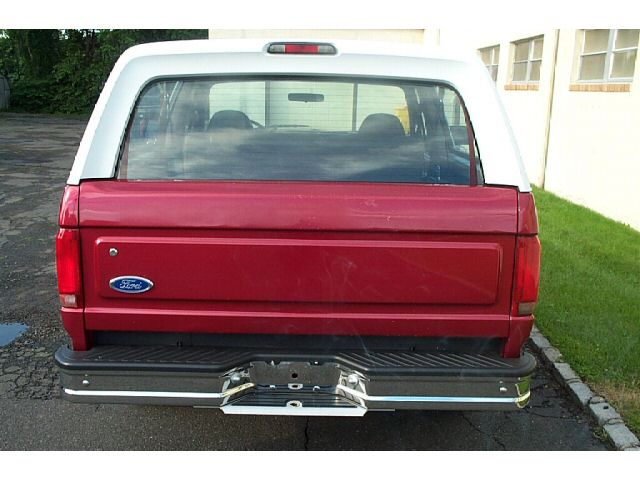 Red and white Ford Bronco rear view. Chrome bumper and Ford emblem visible