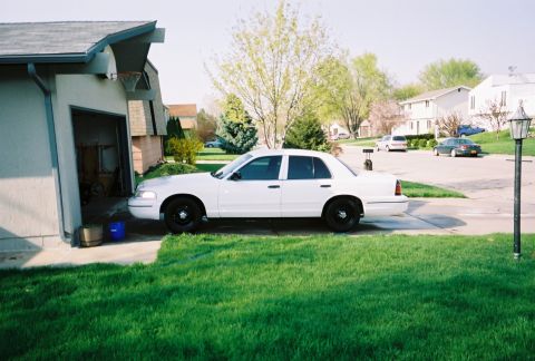 2000 Ford Crown Victoria - A white 2000 Ford Crown Victoria is parked in a suburban driveway next to a garage.