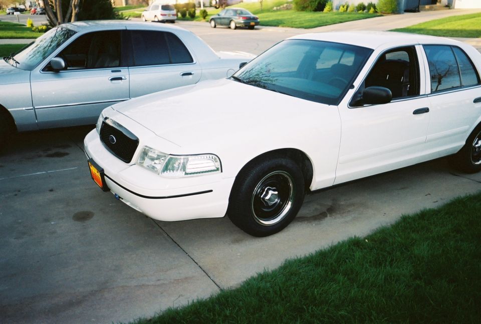 White 2000 Ford Crown Victoria parked next to a silver sedan on a driveway