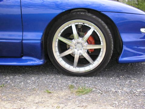 1994 Ford Probe - Close-up of a blue car's front wheel and fender, showing aftermarket modifications.