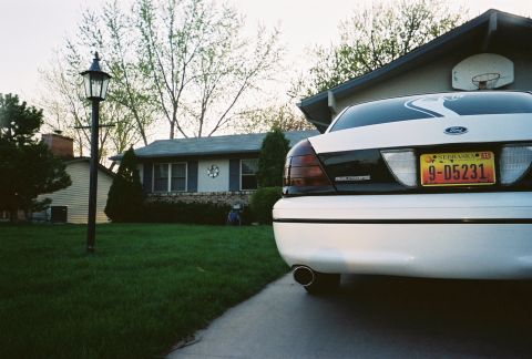 2000 Ford Crown Victoria - Rear view of a white 2000 Ford Crown Victoria parked in a driveway, showing its taillights and license plate.