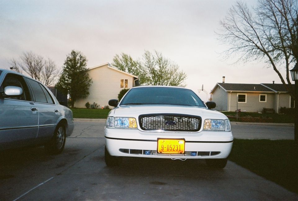 White 2000 Ford Crown Victoria parked in driveway, another car to the left