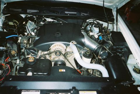 2000 Ford Crown Victoria - The engine bay of a vehicle, showing various mechanical parts and fluid reservoirs.