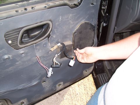 2003 Ford Ranger - Close-up of a vehicle's interior door panel with the speaker removed, revealing wiring and the door handle mechanism.