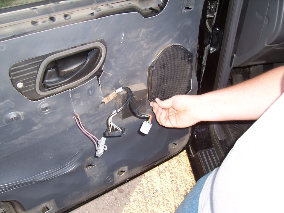 Interior door panel with speaker removed, showing wiring and door handle
