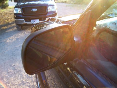 2003 Ford Ranger - A dark Ford F-150 truck is visible, with its grille and license plate clearly seen. Another vehicle is in the foreground.