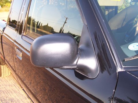 2003 Ford Ranger - Side view of a black 2003 Ford Ranger pickup truck, showing the door handle, side mirror, and part of the front tire.