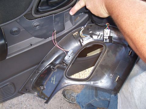 2003 Ford Ranger - Close-up of a car door panel being disassembled, revealing internal wiring and mounting points.