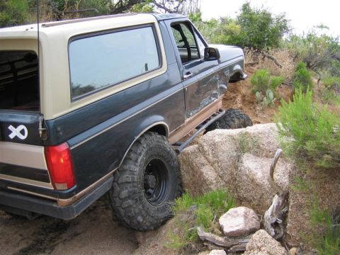 1994 Ford Bronco - This Ford Bronco is navigating a rocky off-road trail with its tires on large boulders.