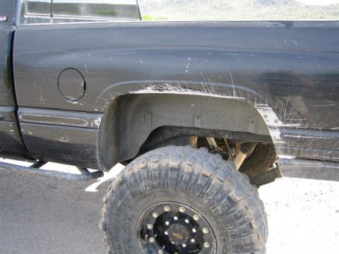 1994 Ford Bronco - Close-up of the rear wheel well and tire of a black pickup truck.