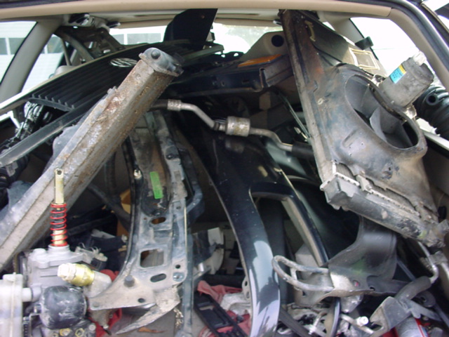 Pile of car parts, including a black dashboard section and metal bracing, filling the interior of a vehicle