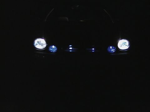 1999 Ford Taurus - The front of a car is visible in the dark, showing its headlights and grille.