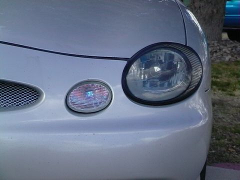 1999 Ford Taurus - A close-up view of the front corner of a silver vehicle, highlighting the headlight assembly.