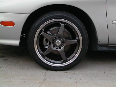 1999 Ford Taurus - Close-up of a flat tire on a silver car with custom black rims.