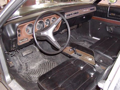 1988 Ford Bronco - The interior of a 1973 Dodge Charger features a distinctive dashboard, steering wheel, and center console with woodgrain accents.