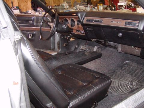 1988 Ford Bronco - Interior of a 1973 Dodge Charger, a wood-grain dash and black vinyl seats.