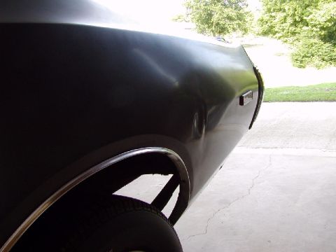 1988 Ford Bronco - A close-up shot of a car's rear fender reveals a dent and the edge of a tire.
