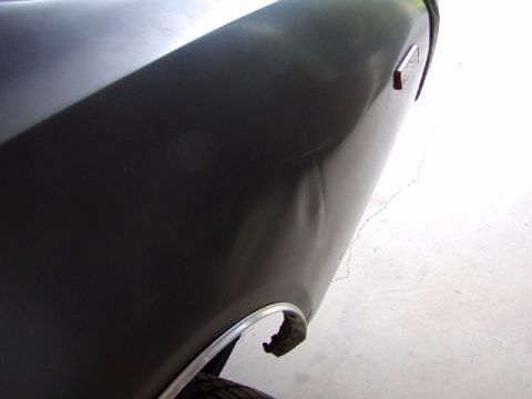 1988 Ford Bronco - Close-up view of a dented fender on a dark-colored vehicle, showing chrome trim around the wheel well.