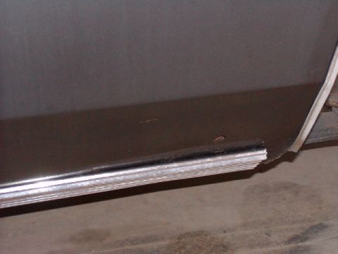 1988 Ford Bronco - A close-up shot of a vehicle's lower body panel and trim, showing some wear and rust.
