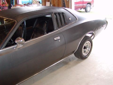 1988 Ford Bronco - A dark gray 1970s Dodge Charger is parked inside a garage, with a red pickup truck visible outside.