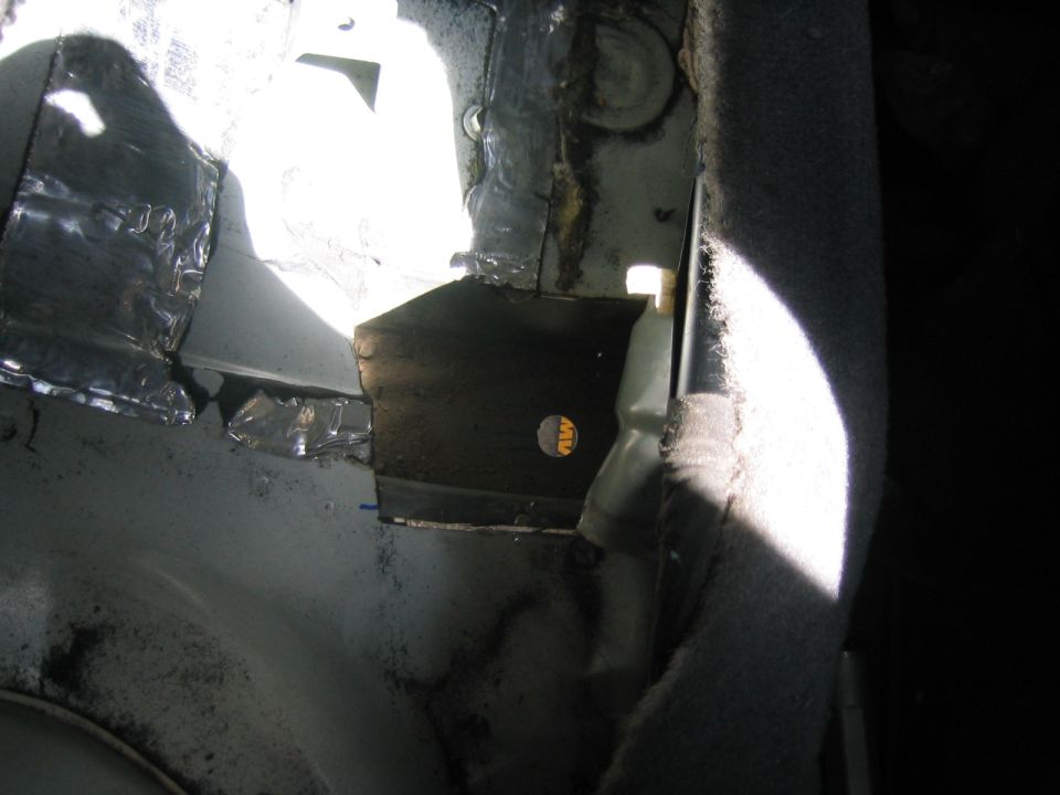 Close-up of metal bracing and insulation in a vehicle's interior, possibly under repair