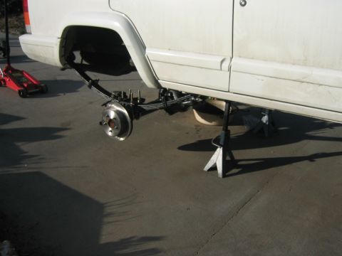 1997 Jeep Cherokee - The rear suspension of a white 1997 Jeep Cherokee is removed and the vehicle is supported by jack stands.
