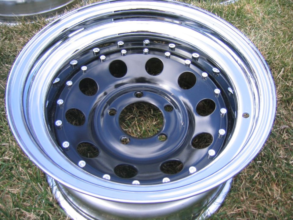 Chrome-lip black-center 5-lug steel wheel lying face-up on grass
