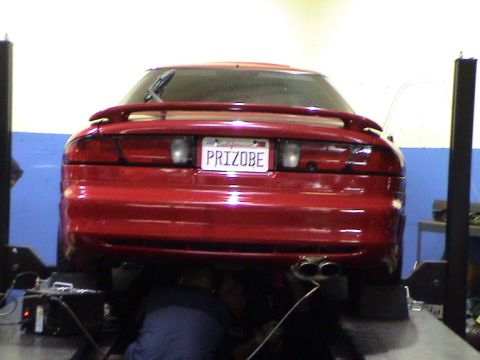 1997 Ford Probe - A red coupe is shown from the rear on a vehicle lift in a garage setting.