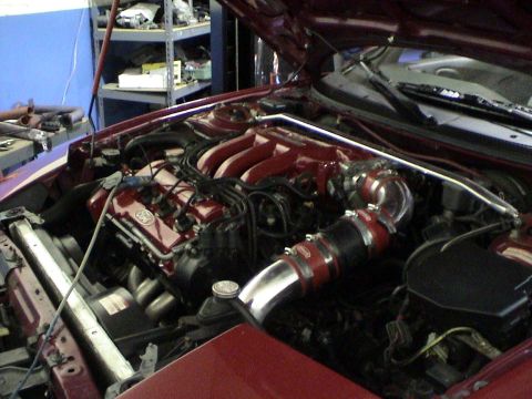 1997 Ford Probe - Close-up of a car's engine bay, showing custom intake piping and a red-painted manifold.