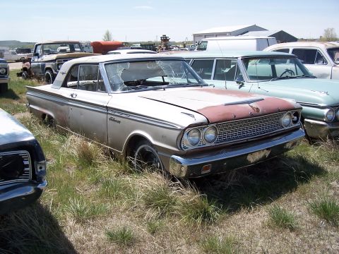 1968 Ford Coupe - A weathered coupe with a distinctive grille and dual headlights is parked in a field of tall grass.