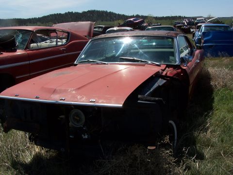 1968 Ford Coupe - Junkyard scene with a 1968 Ford Coupe in the foreground, other vehicles visible.