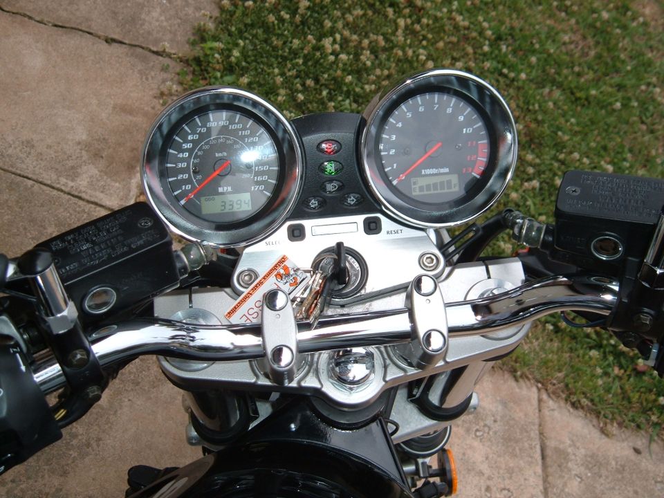 Motorcycle dashboard with two analog gauges, keys in ignition, and chrome handlebars