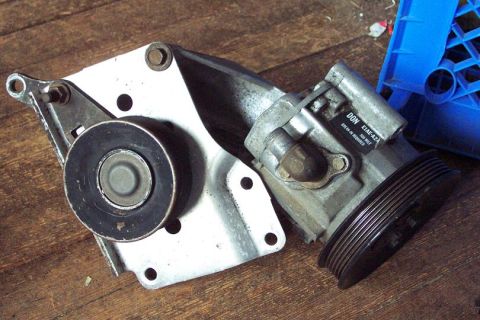 1985 Ford Crown Victoria LTD - A power steering pump assembly, including a pulley and bracket, rests on a wooden surface.