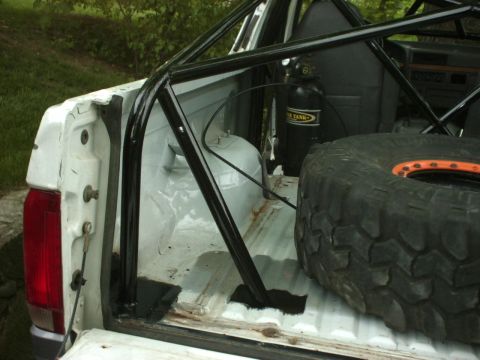1995 Ford Bronco - Interior view of a 1995 Ford Bronco bed, showing a roll cage, spare tire, and a tank.