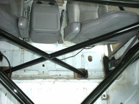 1995 Ford Bronco - The interior of a vehicle is shown with a prominent roll cage and gray seating.