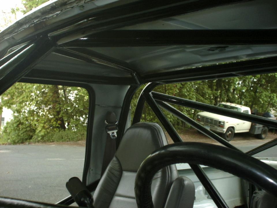 Interior roll cage with view of a white flatbed truck outside
