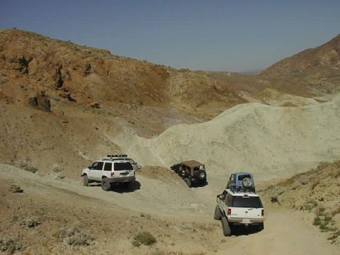 1997 Ford Ranger - Multiple SUVs and a Jeep traverse a desert terrain under a clear blue sky.