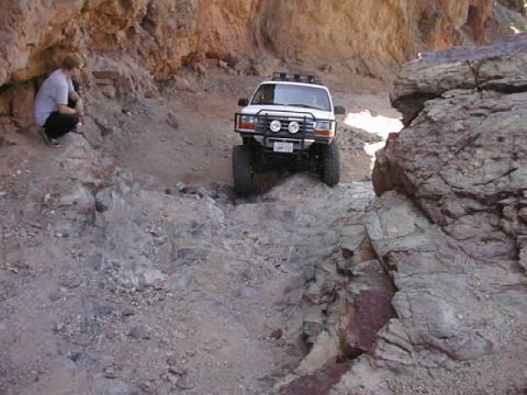 1997 Ford Ranger - A person watches an off-road vehicle navigate a narrow, rocky path through a canyon.