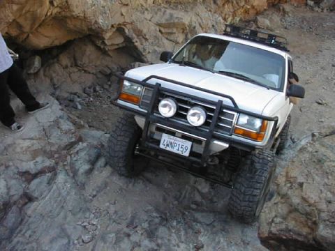1997 Ford Ranger - A white 1997 Ford Ranger navigates a steep, rocky trail with a person standing nearby.