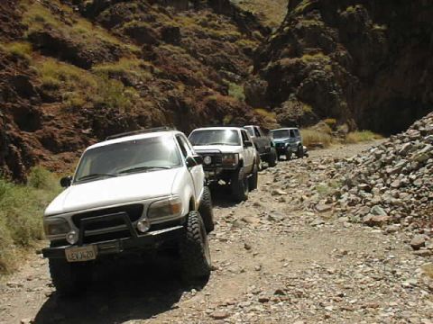 1997 Ford Ranger - A convoy of off-road vehicles navigates a rocky canyon road.