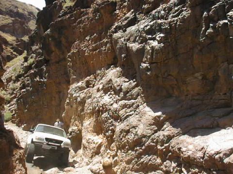 1997 Ford Ranger - A white pickup truck drives through a tight, rocky canyon, with a person standing near the vehicle.
