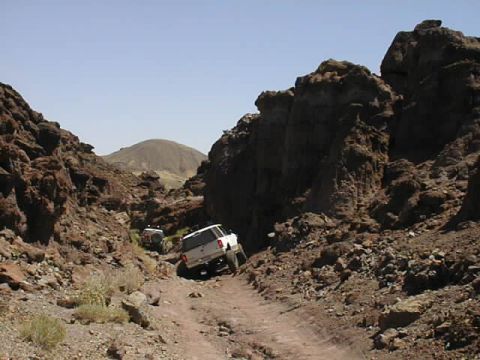 1997 Ford Ranger - Two SUVs traverse a , rocky terrain on a sunny day.