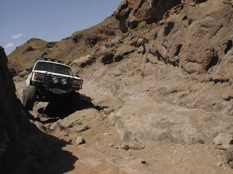1997 Ford Ranger - A white 1997 Ford Ranger navigates a challenging rocky terrain under a clear blue sky.