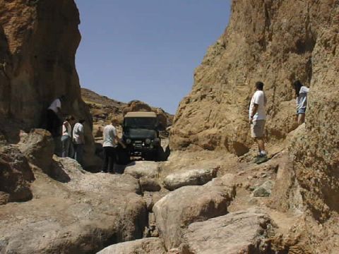 1997 Ford Ranger - A Jeep Wrangler drives through a tight, rocky canyon path with onlookers.