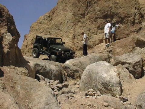 1997 Ford Ranger - A Jeep navigates a challenging rocky terrain under a clear blue sky.