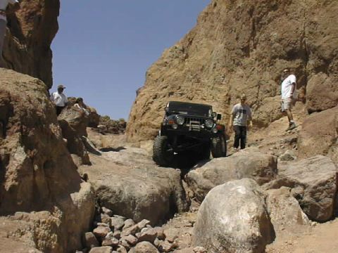 1997 Ford Ranger - A black Jeep Wrangler tackles a challenging rocky path in a desert canyon environment.