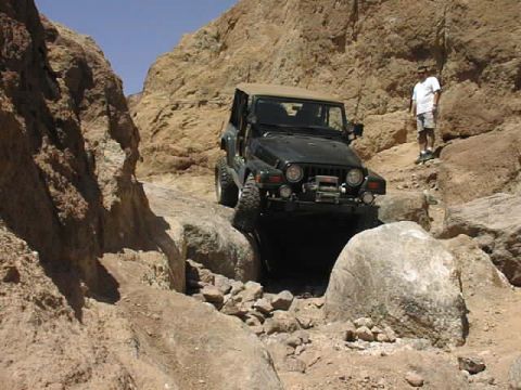 1997 Ford Ranger - A Jeep Wrangler carefully maneuvers through a narrow, rocky passage in a desert canyon.