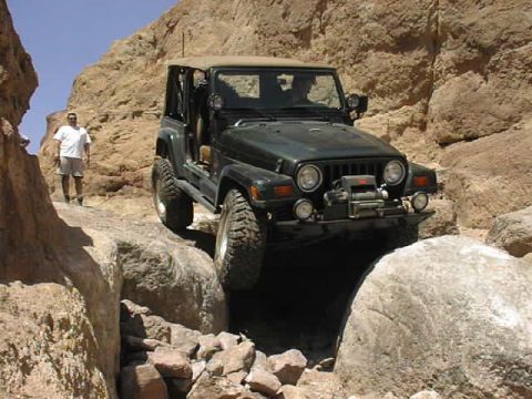1997 Ford Ranger - Jeep Wrangler TJ on a rocky off-road trail with a person watching.