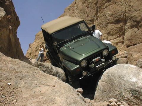 1997 Ford Ranger - A Jeep Wrangler is shown navigating a narrow, rocky canyon path under a clear blue sky.
